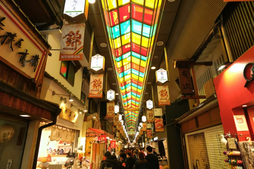 Vibrant lanterns and shops in Nishiki Market, a stop for local food on Kyoto free walking tours