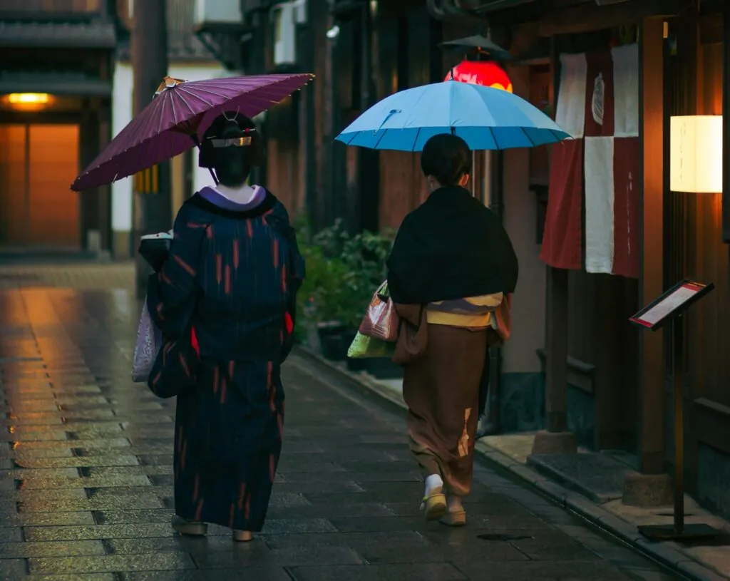 Visitors walking through Gion District with umbrellas, showcasing Kyoto’s charm during free walking tours