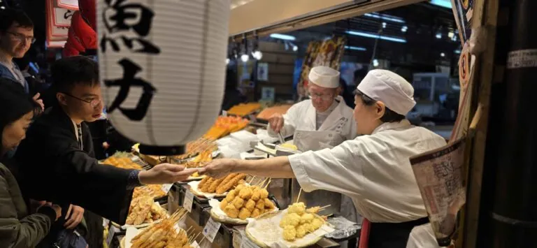 Chefs preparing tempura and other street food at a vibrant Nishiki Kyoto market, a culinary highlight of Kyoto free walking tours