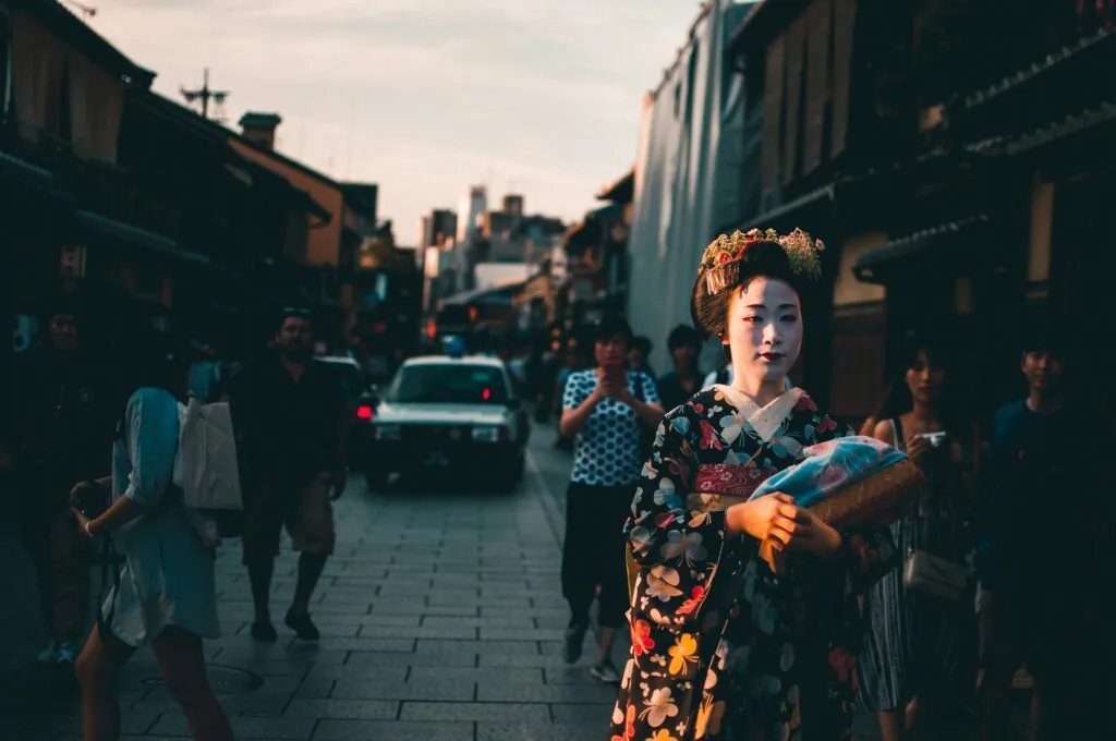 A geisha walking through Kyoto's historic Gion District at sunset, a cultural highlight of Kyoto free walking tours