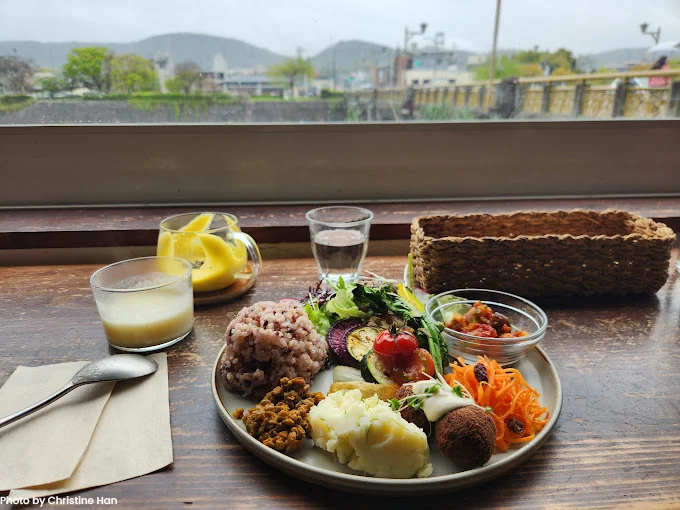 A traditional vegan Kaiseki meal featuring seasonal vegetables and tofu, enjoyed with a scenic view of Kyoto’s mountains