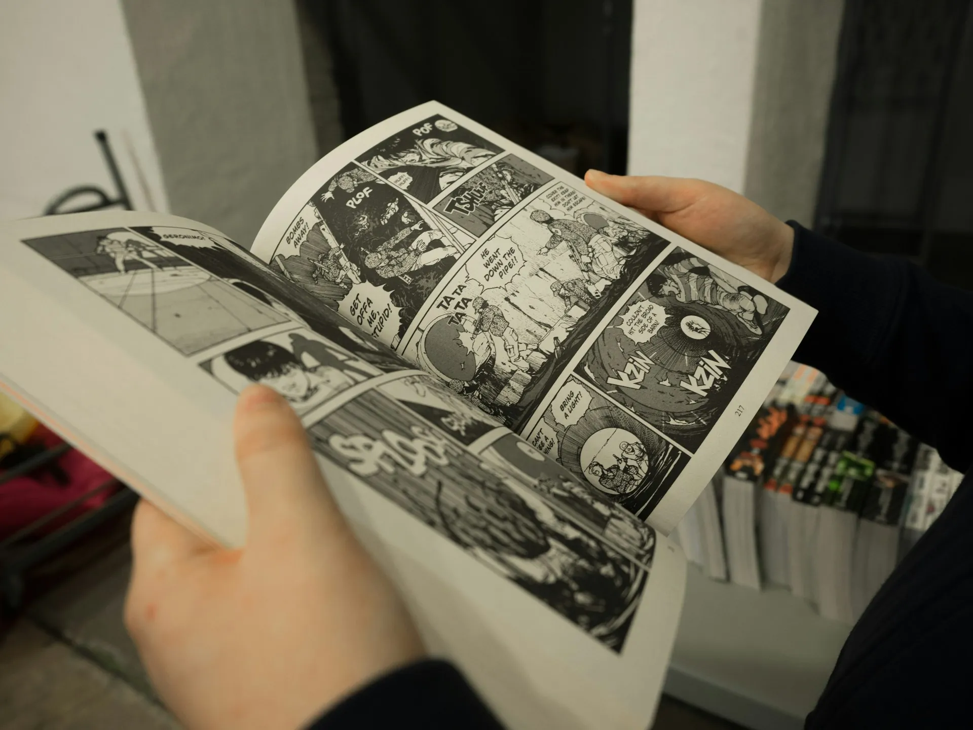 Person reading a manga in Kyoto anime district, surrounded by shelves of comics and graphic novels